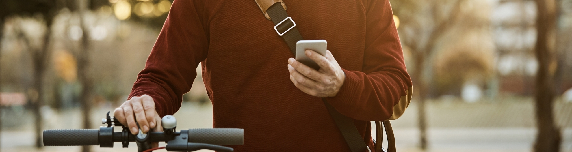 Man standing by bike looking at phone and smiling.